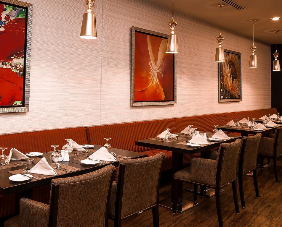 Al Ghufran Safwah Hotel Makkah Mekka Buitenkant foto The photo shows the interior of a restaurant. There are several tables set with white tablecloths, neatly folded napkins, and glassware. The walls are decorated with colorful artwork, including abstract paintings. The lighting is ambient, provided by