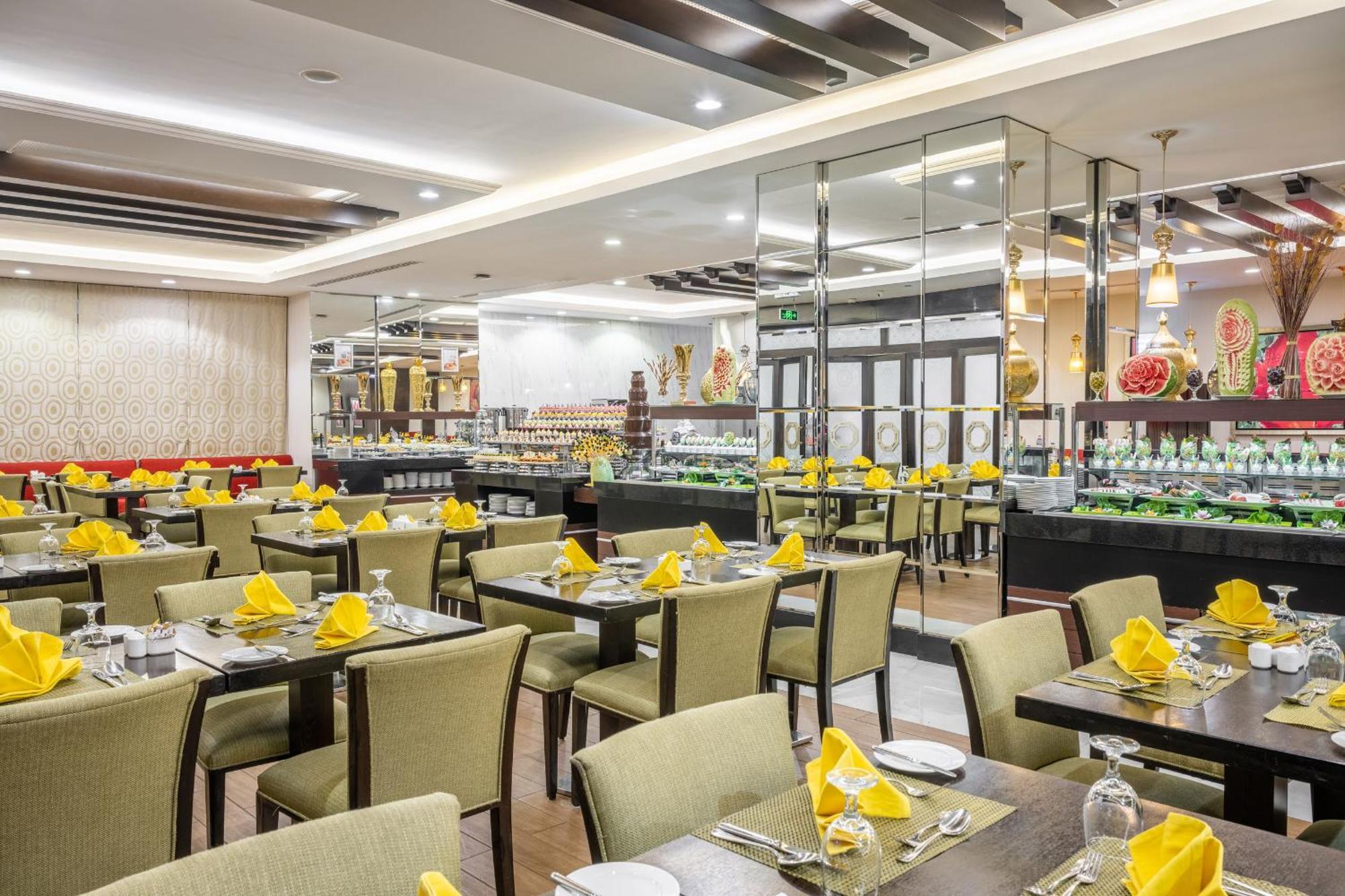 Al Ghufran Safwah Hotel Makkah Mekka Buitenkant foto The photo shows an interior of a restaurant. The dining area features several tables covered with green tablecloths, each set with white plates, silverware, and folded yellow napkins. The chairs are also green, complementing the table decor. In the b