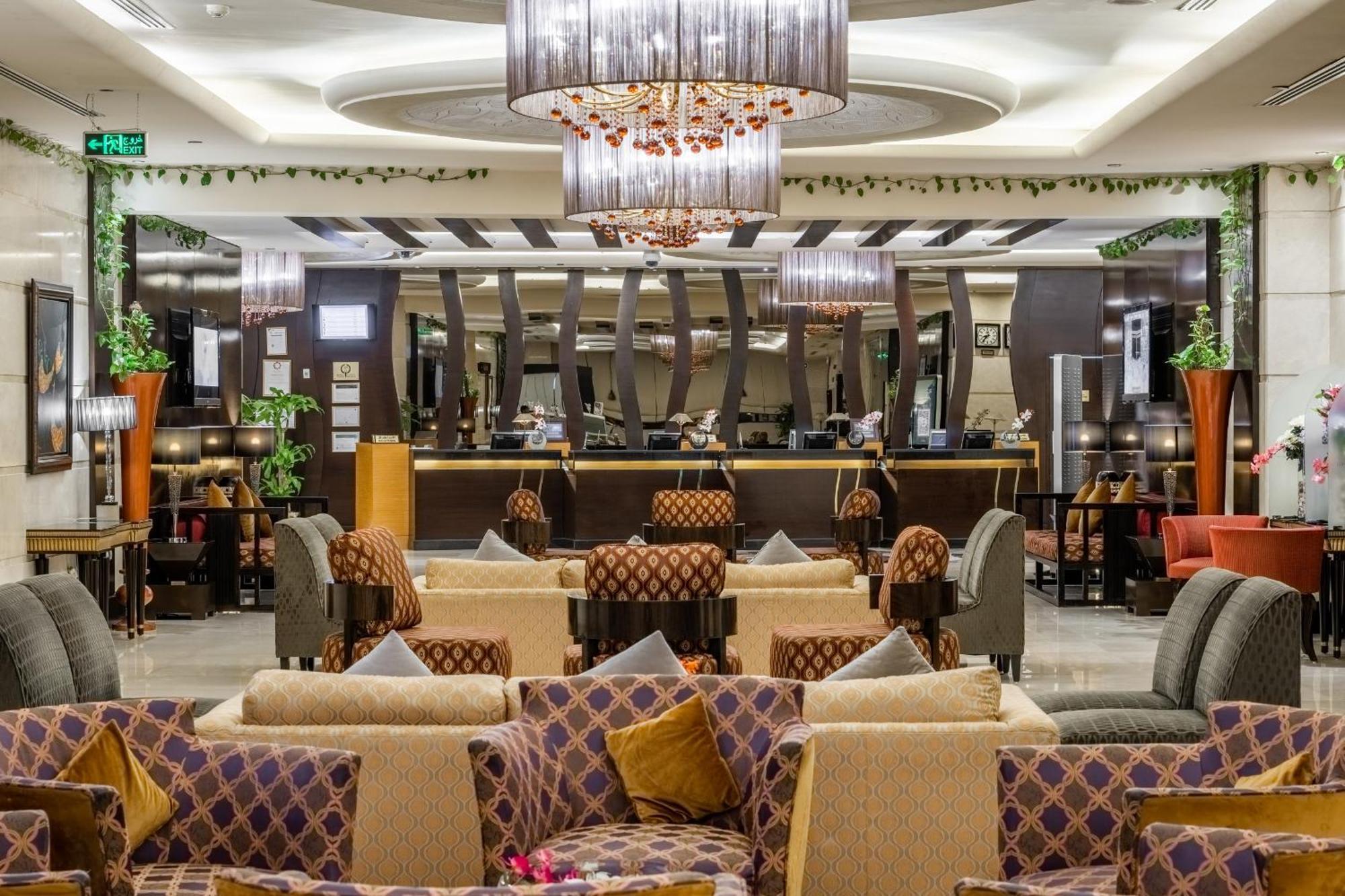 Al Ghufran Safwah Hotel Makkah Mekka Buitenkant foto The photo shows a stylish interior of a lounge or lobby area, featuring a mix of seating arrangements. There are plush sofas with colorful cushions scattered throughout the space, creating a cozy atmosphere. The room is well-lit with modern chandelie