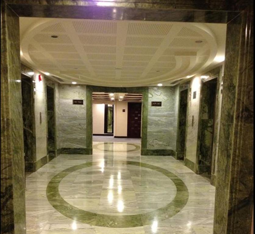 Al Ghufran Safwah Hotel Makkah Mekka Buitenkant foto The photo shows the interior of a modern elevator lobby. The walls are decorated with a prominent green marble, and the floor features a polished marble design with circular patterns. There are several elevator doors visible on one side, and the spac